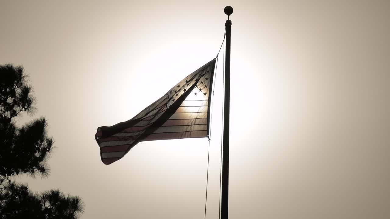 Tattered And Backlit American Flag Waving In The Wind