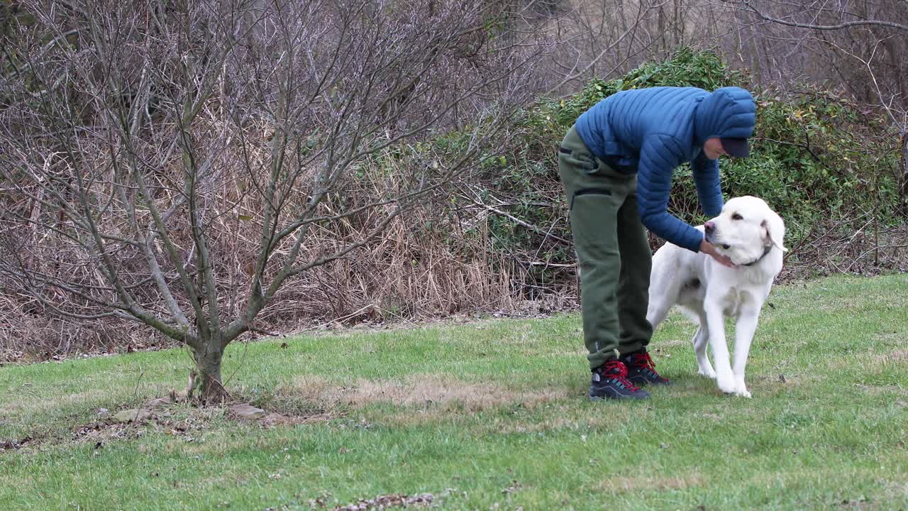 un joven blanco juega con su gran cachorro blanco de los pirineos en el patio en un frío día de invierno en frankfort kentucky