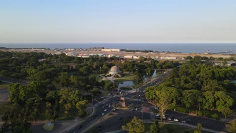 dolly in of monumento to the spanish and palermo woods leading to galileo galilei planetarium with rio de la plata river in background, buenos aires, argentina