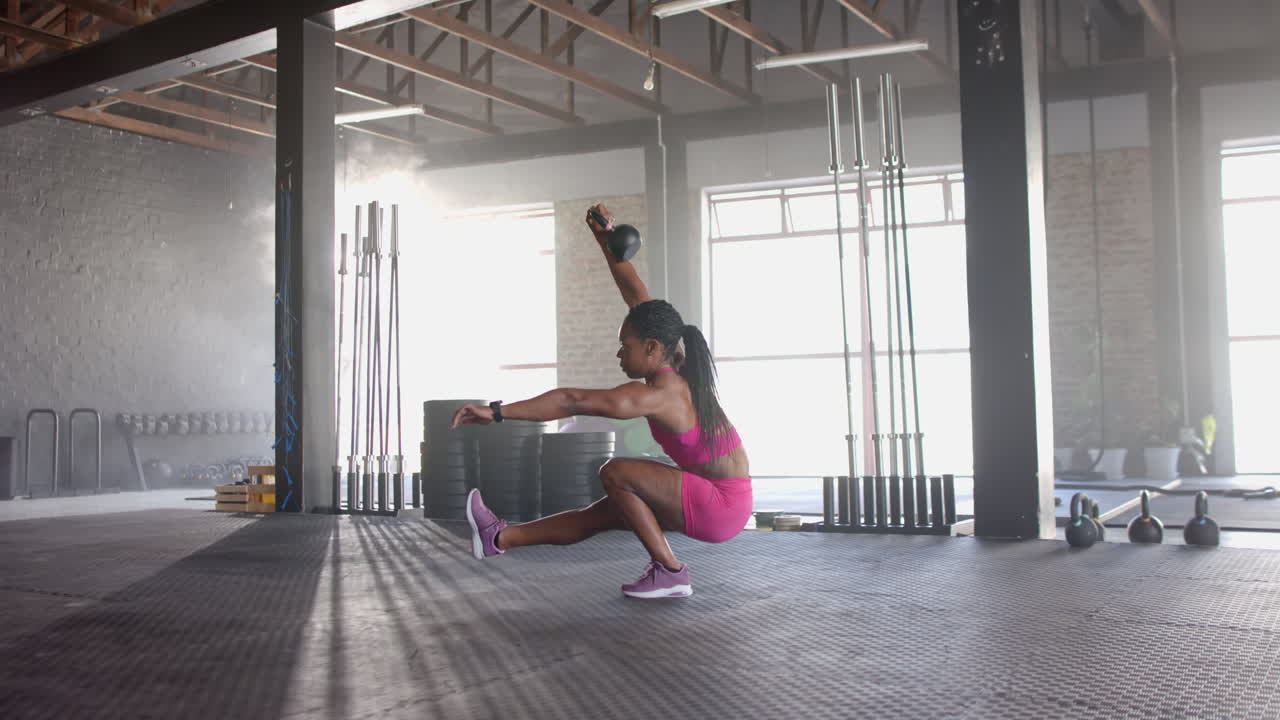 Performing one-legged squat with kettlebell, woman exercising in gym