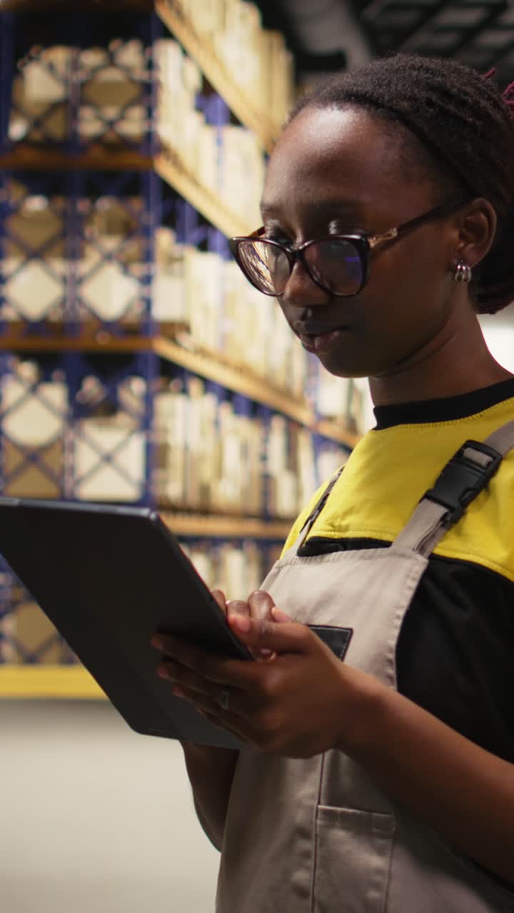 Vertical Video Black female industrial clerk working on order processing tasks with tablet