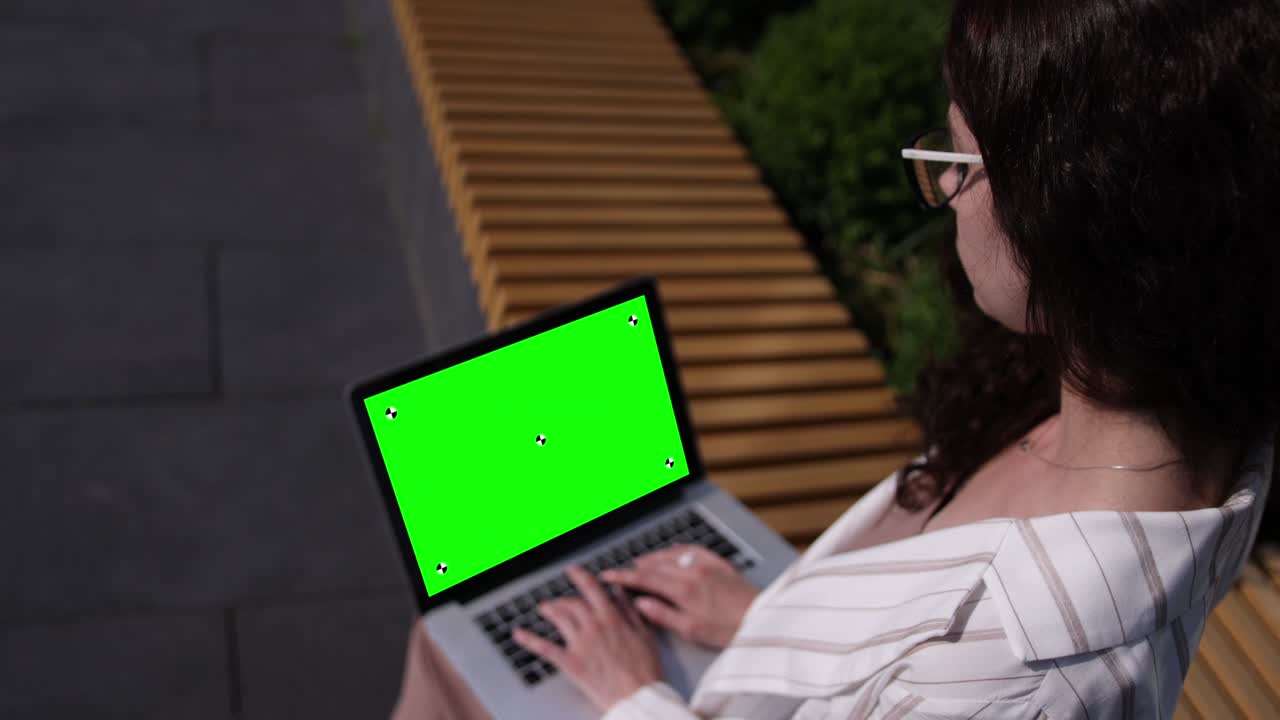 computadora portátil en los regazos de las mujeres al aire libre. vista desde la parte de atrás de la mujer en blanco