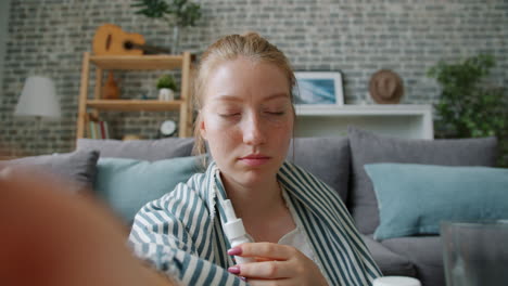 woman using nasal spray at home