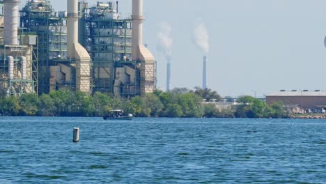 power station by a lake with steam or smoke pouring from the smoke stacks, chimney or chimley