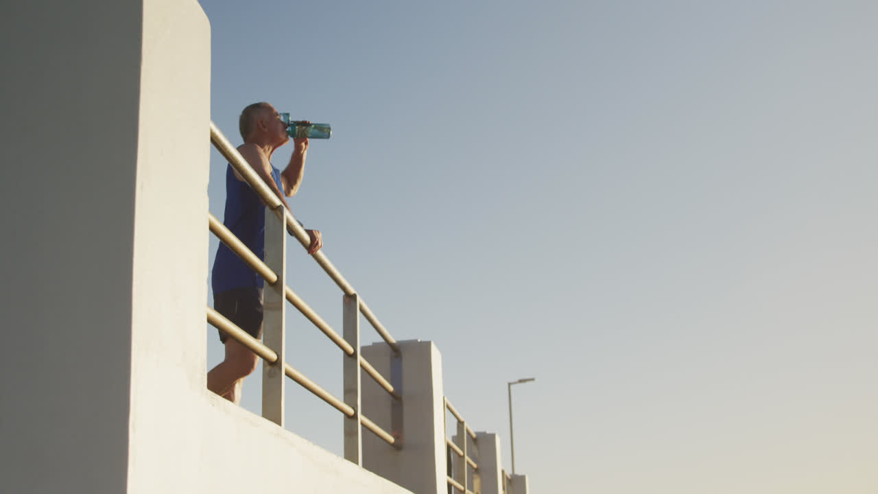 hombre mayor bebiendo agua en el paseo marítimo