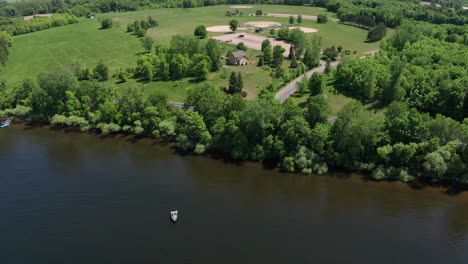 Tiro-Aéreo-Bajo-Volando-Sobre-Un-Lago-E-Inclinándose-Hacia-Arriba-Para-Revelar-Una-Casa-Histórica-De-Inmigrantes-Suecos-En-Lindstrom,-Minnesota