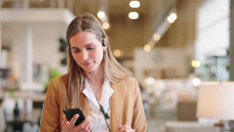 associate walks aisle, smiling as she concentrates on smartphone at normal pace