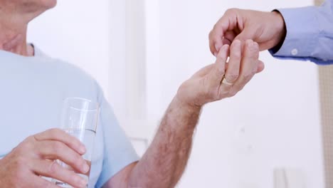 male nurse giving pills to senior man