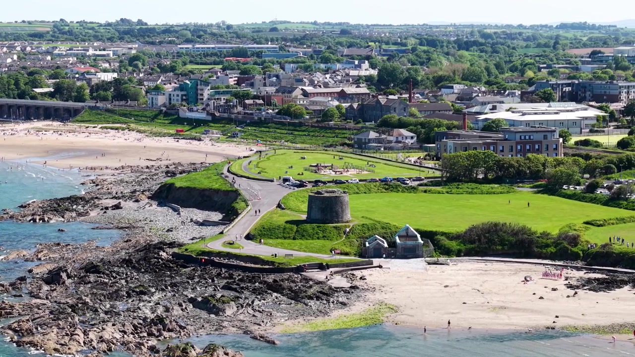 Pueblo de Balbriggan y playa de arena, costero con torre y paisaje urbano aéreo. Irlanda, soleado.