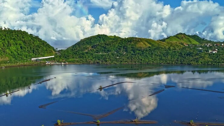 A time lapse of clouds moving above a perfectly still, aquaculture fish pond, used to farm shrimp in Surigao - Philippines
