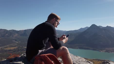 caminante en la cima de la montaña enviando mensajes de texto a kananaskis, alberta, canadá