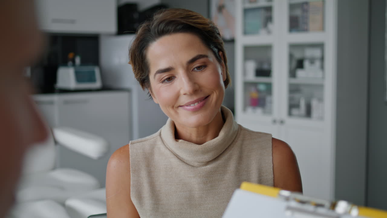 Woman signing cosmetological agreement for procedure in aesthetic clinic closeup