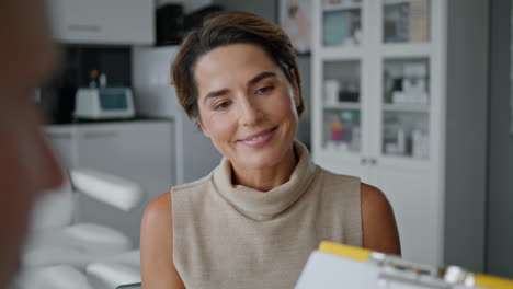 woman signing cosmetological agreement for procedure in aesthetic clinic closeup