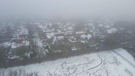 drone pulling back from beautiful suburban neighborhood covered in snow and mist