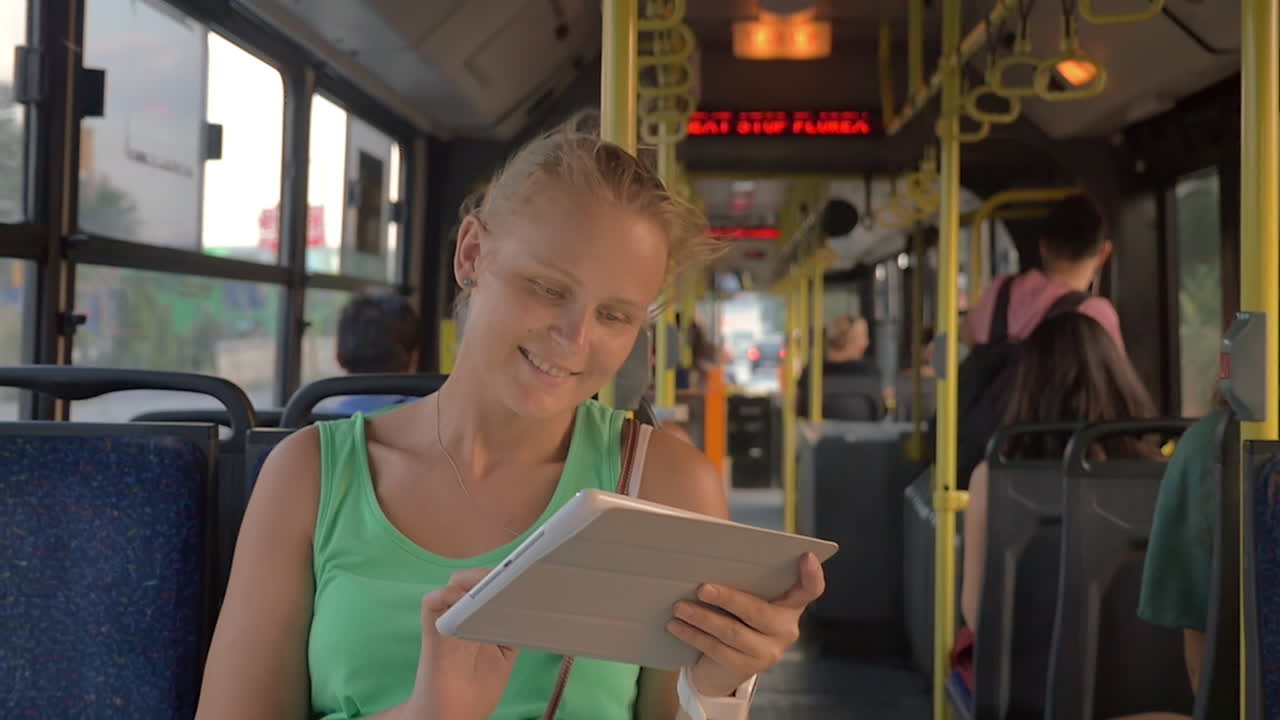 mujer sonriente escribiendo en la tableta en el autobús