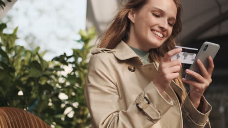 estudiante caucásica haciendo compras en línea en el teléfono inteligente al aire libre.