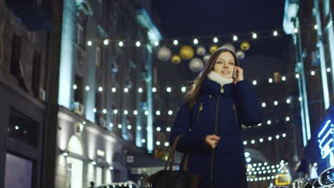 Young-woman-walks-through-the-night-city-talking-on-the-phone