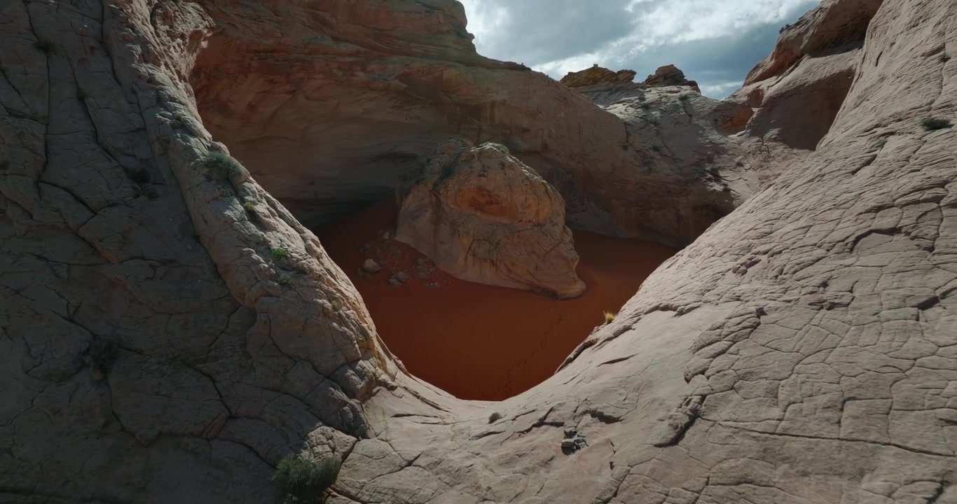 Cosmic Ashtray Utah. Pomarańczowy piasek mineralny spoczywa wewnątrz gładkiej, białej misy z piaskowca z erodowanymi formacjami skalnymi, oddalenie z lotu ptaka