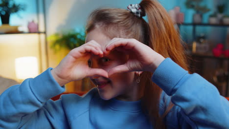 young child kid girl makes symbol of love showing heart sign to camera express romantic feelings