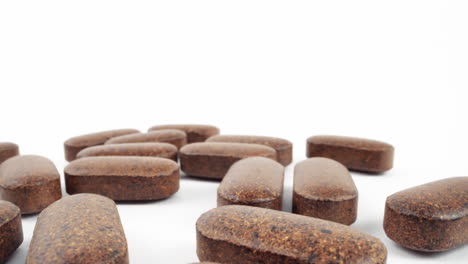 high-key shot of brown herbal pills on a pure white background with soft shadows