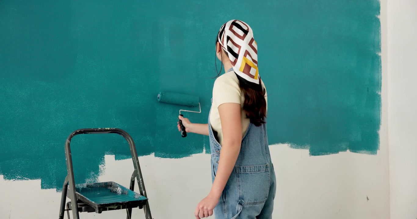 Mujer joven pintando una pared con un rodillo