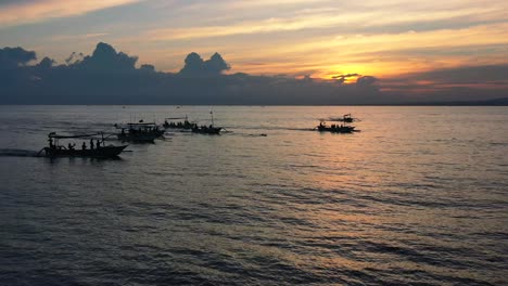 aerial of mass tourism with tourist boats chasing dolphins in tropical waters of lovina bali indonesia at sunrise