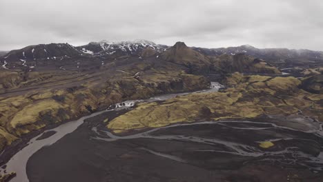vista panorámica de las tierras altas islandesas rodeadas de suelo volcánico negro del desierto con ríos que corren - tiro aéreo circular