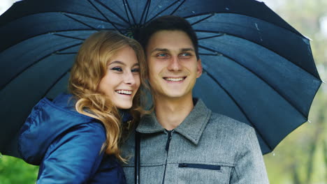 Man-And-Woman-Under-An-Umbrella-The-Rain-Look-Ahead-Laugh-Smile