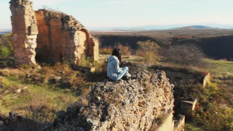 caucasian woman sits on fortress ruins and enjoy panoramic view historical samshvilde site.georgia travel concept