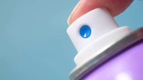 close-up of a finger pressing the nozzle of a purple spray paint can