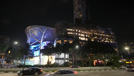 vista nocturna de un edificio moderno y un centro comercial en singapur