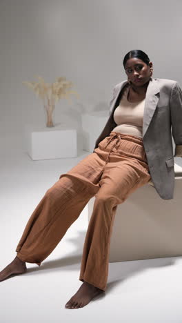 vertical video: model in stylish outfit posing confidently in modern fashion studio setting