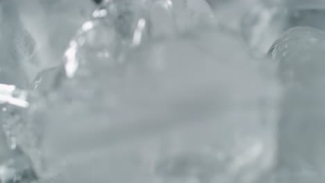 agua vertiendo sobre cubitos de hielo con burbujas que se elevan