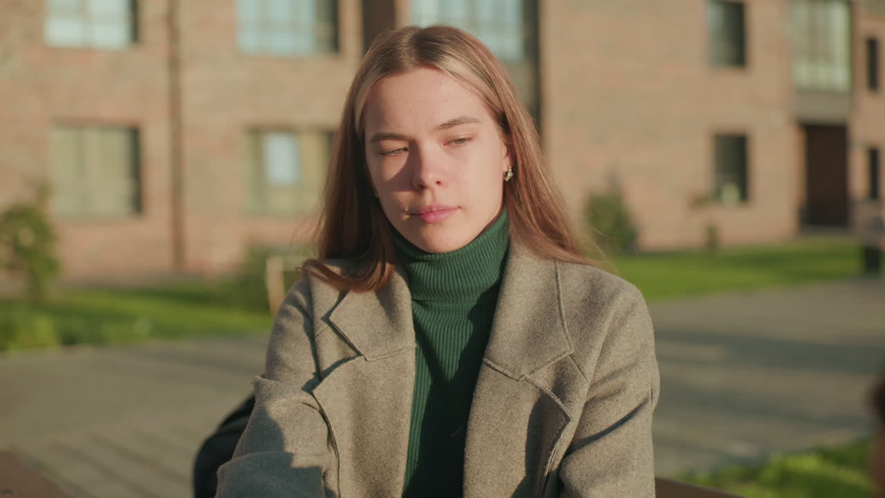Mother hands snack and drink to unhappy child sitting outdoors, child remains unbothered with disappointed expression while mother looks concerned