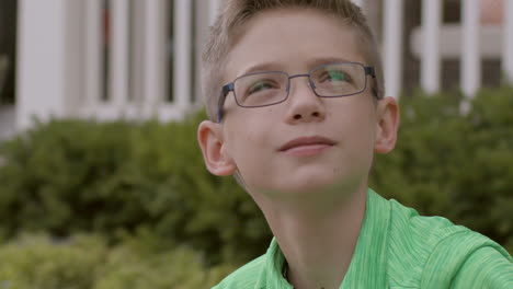 Cute-boy-at-home-in-front-yard-gazes-up-to-the-sky,-close-up