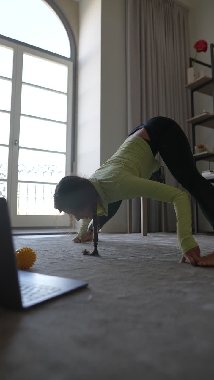mujer practicando yoga en casa usando una computadora portátil