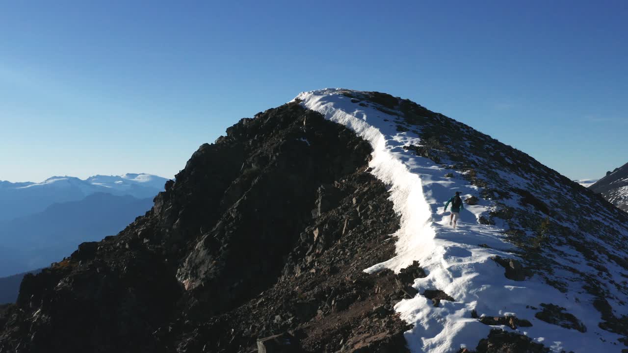 bird eye dolly zoom man trail running montaña rocosa cubierta de nieve empinada