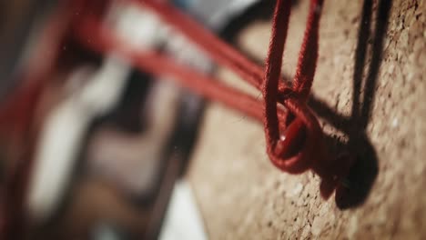 close up of network of red strings meticulously connected on an investigation board, suggesting a complex web of evidence or clues