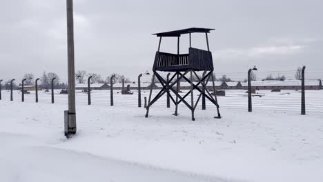 inside auschwitz-birkenau looking towards guard tower and destroyed buildings - winter with snow