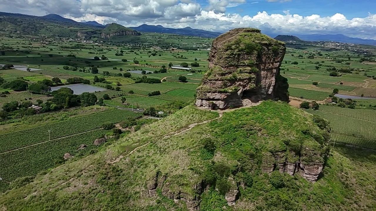 Cảnh quay flycam từ trên không của Cerro de los Hotcakes nổi bật trên nền đất nông nghiệp ở Puebla, Mexico. Khối đá núi lửa được bao quanh bởi những cánh đồng canh tác, đồi núi và vùng nông thôn.