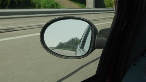 rounded sideview mirror of car, empty no cars behind on road