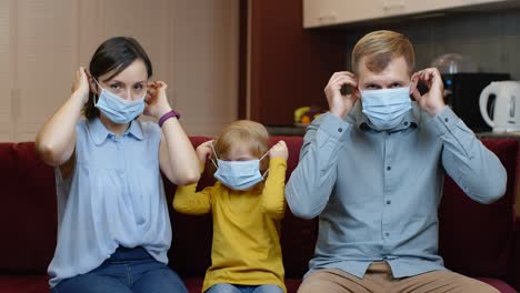 Ausgangssperre-Aufgrund-Der-Coronavirus-Quarantäne:-Mutter,-Vater-Und-Tochter-Legen-Zu-Hause-Medizinische-Masken-Auf-Ihre-Gesichter