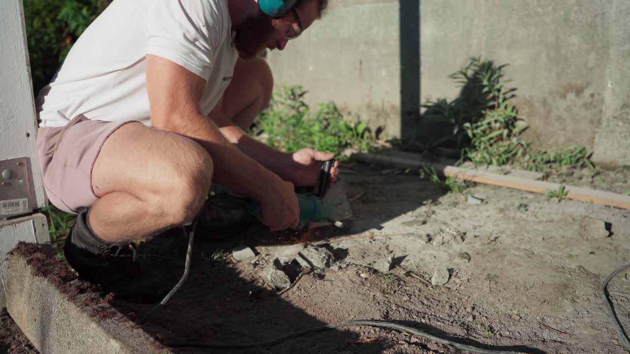 un hombre está usando una molienda angular en la construcción de un invernadero - de cerca