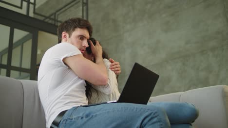 retrato de una pareja asustada mirando la pantalla de la computadora en el sofá en cámara lenta.