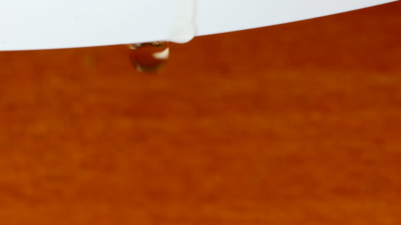 tiro macro de gotas de água caindo de uma borda branca em uma superfície de madeira