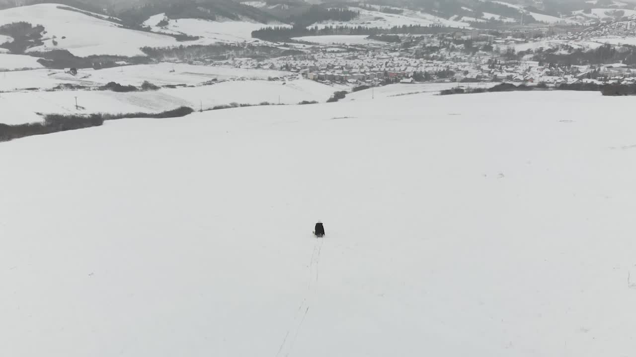 공중 다음 보기, 백그라운드에서 마을과 wintery 눈 풍경에 언덕을 타고 나무 썰매에 소녀