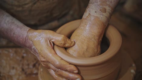 potter working red clay piece close up shot