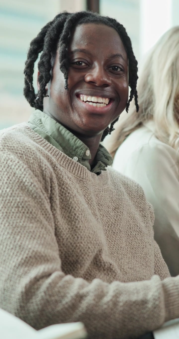 Giovane uomo che sorride durante una riunione in un ufficio luminoso