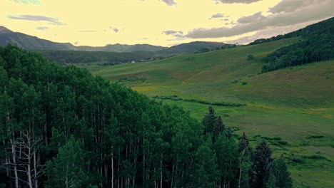 Aerial-over-green-hills-near-the-Crested-Butte-mountain,-Colorado,-USA