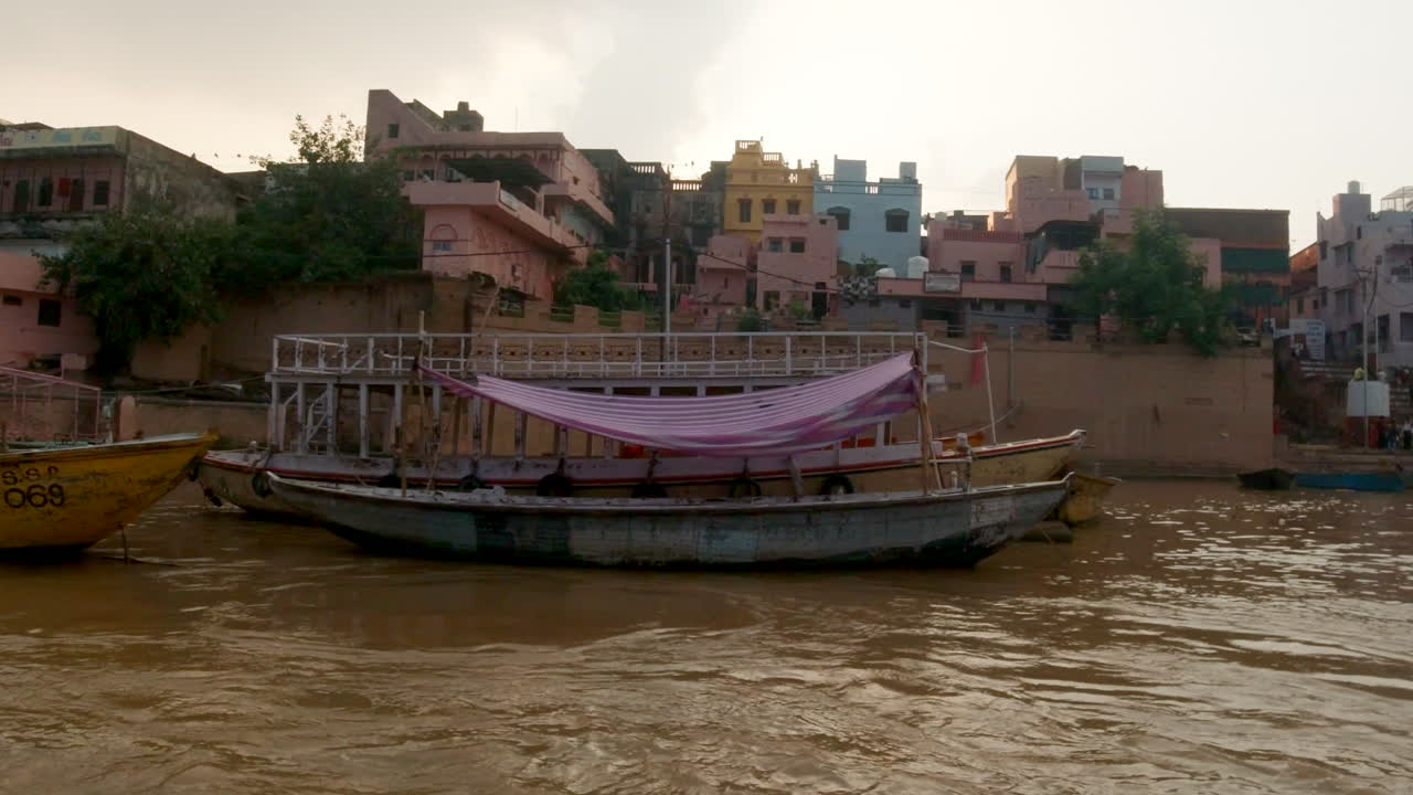 cinematográfica en cámara lenta varanasi india río ganges crucero canal barcos estado del norte gran reunión en la orilla antigua ciudad santa provincia de ghat pradesh paisaje gris nublado por la tarde marrón fangoso a la izquierda